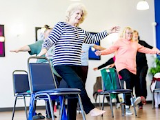People enjoying an exercise class, using chairs as support